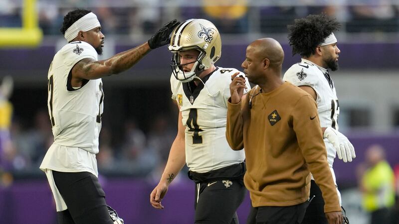 New Orleans Saints wide receiver A.T. Perry, left, pats the helmet of quarterback Derek Carr...